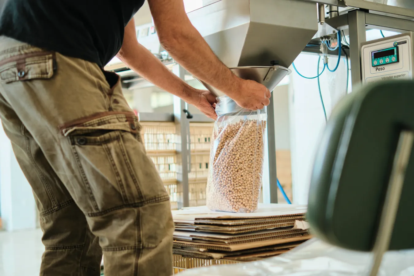 Persona llenando saco de garbanzos ecológicos en instalación de envasado de Hazialdeko