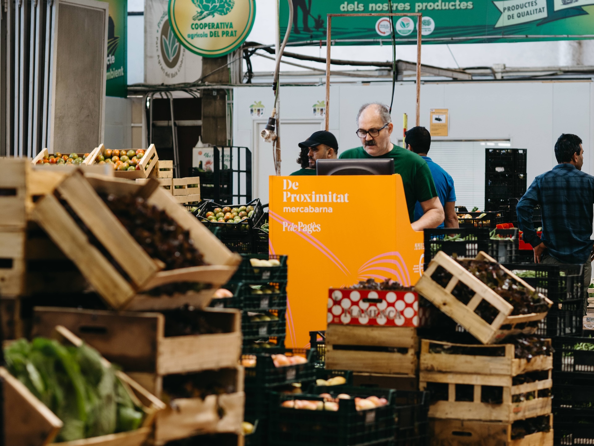 Personas productoras locales y cooperativas en Mercabarna con cajas de frutas y hortalizas de circuito corto