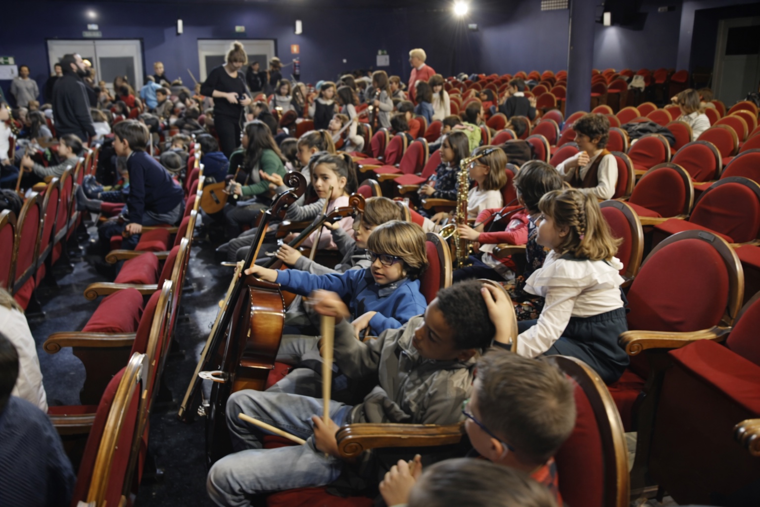 Niños y niñas de la Orquesta Escuela del Barrio con instrumentos en un teatro de Madrid