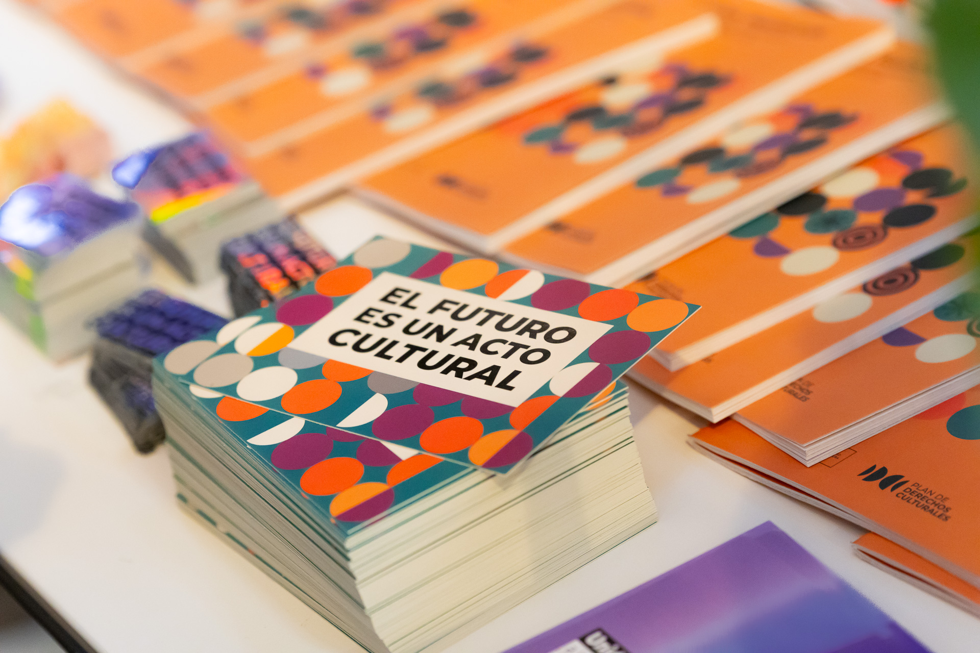 Materiales impresos de la jornada sobre una mesa, junto a tarjetas con el mensaje «El futuro es un acto cultural».